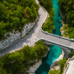 Aerial view of Napoleon Bridge crossing the Soča River with winding roads and forest
